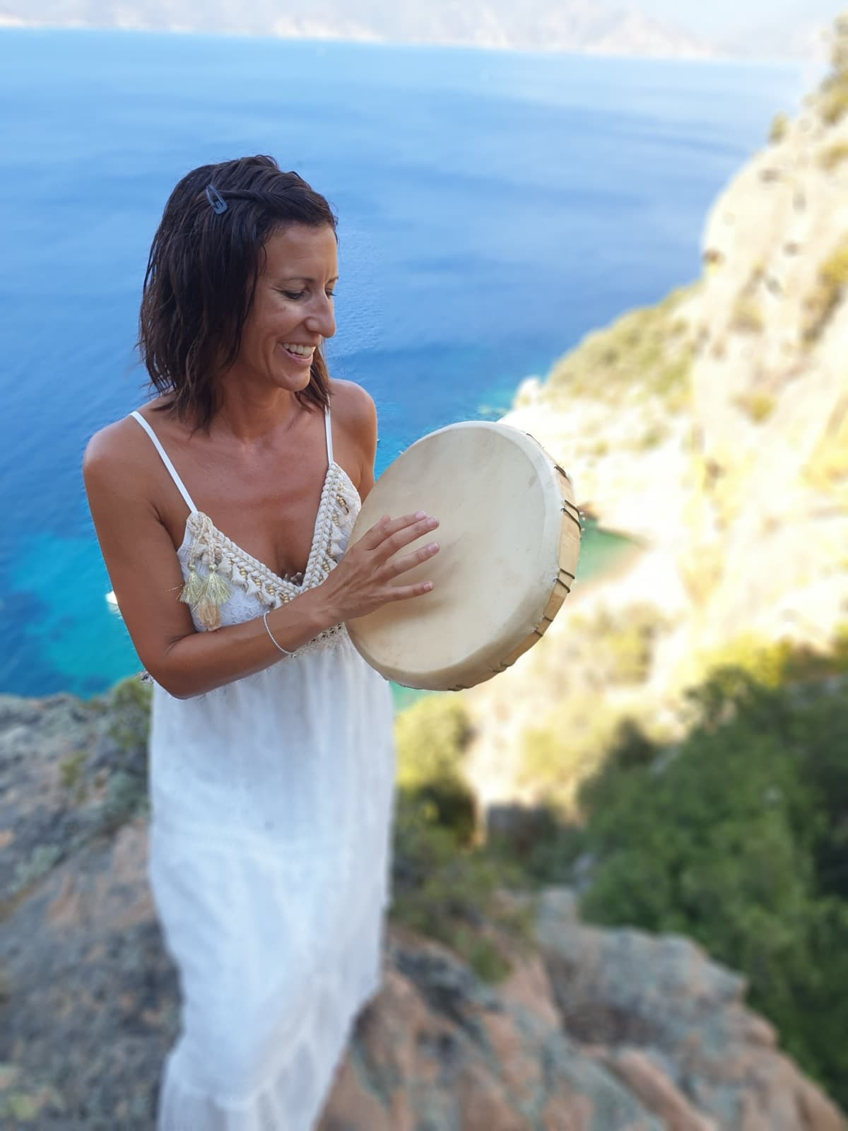 Céline Dusseval avec son tambour, sourire lumineux, mer turquoise