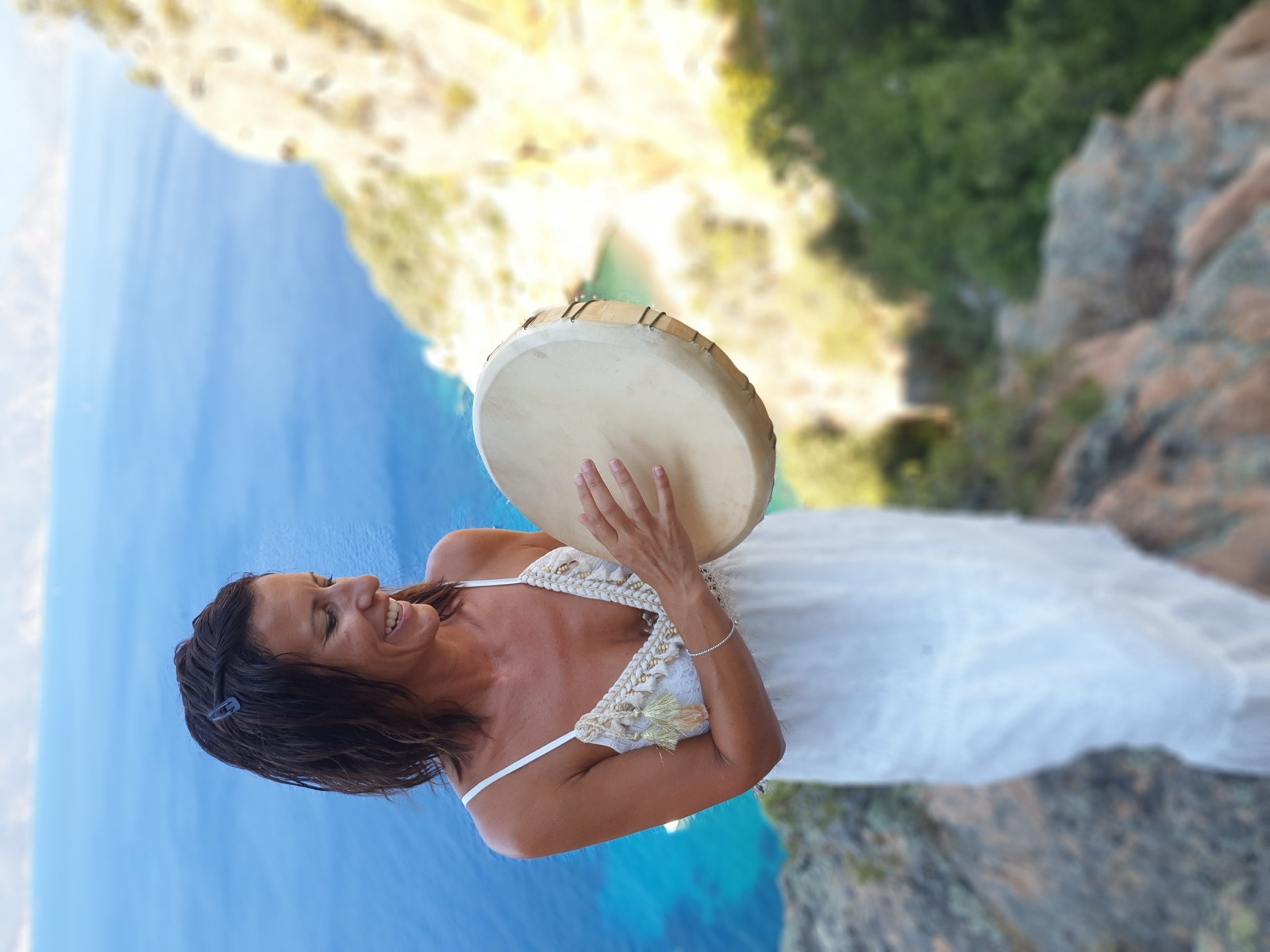 Céline Dusseval avec son tambour, sourire lumineux, mer turquoise